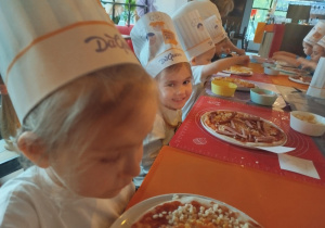 Dzieci komponują swoją pizzę - układają na cieście wybrane przez siebie składniki