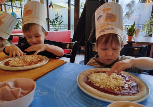 Dzieci komponują swoją pizzę - układają na cieście wybrane przez siebie składniki