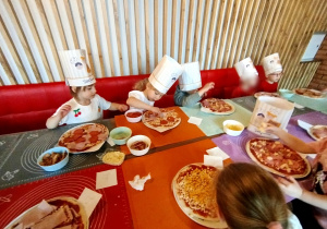 Dzieci komponują swoją pizzę - układają na cieście wybrane przez siebie składniki