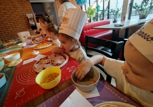 Dzieci komponują swoją pizzę - układają na cieście wybrane przez siebie składniki