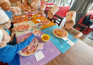 Dzieci komponują swoją pizzę - układają na cieście wybrane przez siebie składniki