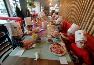 Dzieci komponują swoją pizzę - układają na cieście wybrane przez siebie składniki