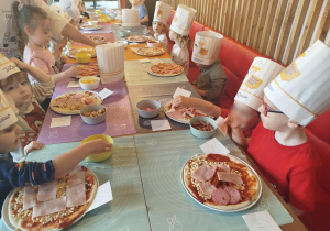 Dzieci komponują swoją pizzę - układają na cieście wybrane przez siebie składniki