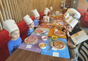 Dzieci komponują swoją pizzę - układają na cieście wybrane przez siebie składniki