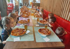 Dzieci zajadają się zrobionymi przez siebie pizzami