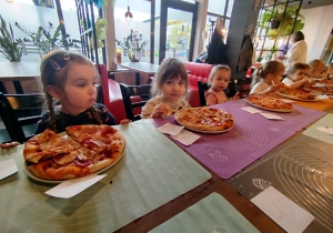 Dzieci zajadają się zrobionymi przez siebie pizzami