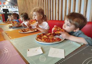 Dzieci zajadają się zrobionymi przez siebie pizzami