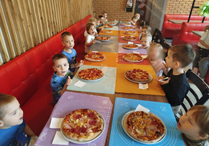 Dzieci zajadają się zrobionymi przez siebie pizzami
