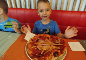 Chłopiec pokazuje swoja pizzę