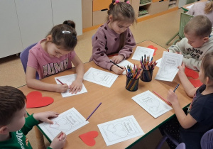 Dzieci przy stolikach wykonują kartki walentynkowe