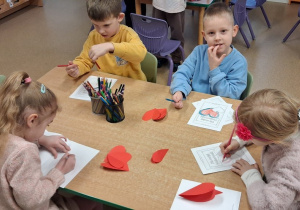Dzieci przy stolikach wykonują kartki walentynkowe