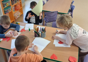 Dzieci przy stolikach wykonują kartki walentynkowe