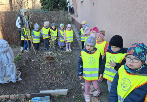 Dzieci oglądają kolejny gródek za blokiem w którym jest owinięta włókniną róża
