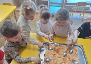 Dzieci smarują pizzę sosem pomidorowym
