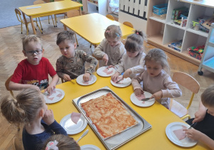 Dzieci smarują pizzę sosem pomidorowym