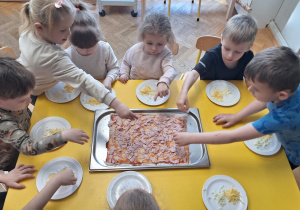 Dzieci układają szyneczkę i serek na pizzy
