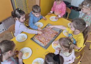 Dzieci układają szyneczkę i serek na pizzy