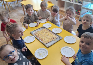 Dzieci układają szyneczkę i serek na pizzy
