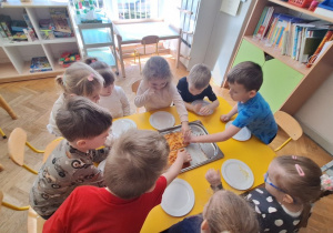 Dzieci jedzą przygotowaną przez siebie pizzę