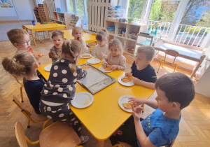 Dzieci jedzą przygotowaną przez siebie pizzę