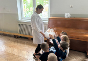 Prowadząca wykonuje eksperymenty z suchym lodem, powiada o nich dzieciom i angażuje dzieci do części zabaw z suchym lodem