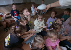 Prowadząca wykonuje eksperymenty z suchym lodem, powiada o nich dzieciom i angażuje dzieci do części zabaw z suchym lodem