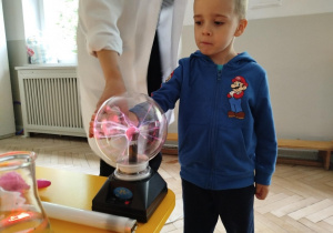 Prowadząca wykonuje eksperymenty z suchym lodem, powiada o nich dzieciom i angażuje dzieci do części zabaw z suchym lodem