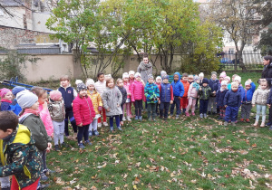 Dzieci stoją w kole w ogrodzie przygotowane do zaśpiewania piosenki o ziemniaku