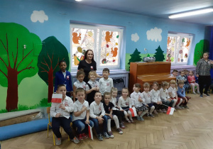 Dzieci z grupy III siedzą na ławeczce i słuchają wierszy o Polsce