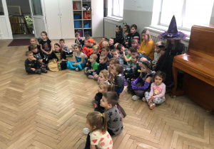 Dzieci siedzą na podłodze słuchają wyników konkursu "Nanajciekawsza ozdoba halloweenowa" "